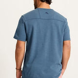 Man wearing a blue t-shirt with a logo on the back against a light background