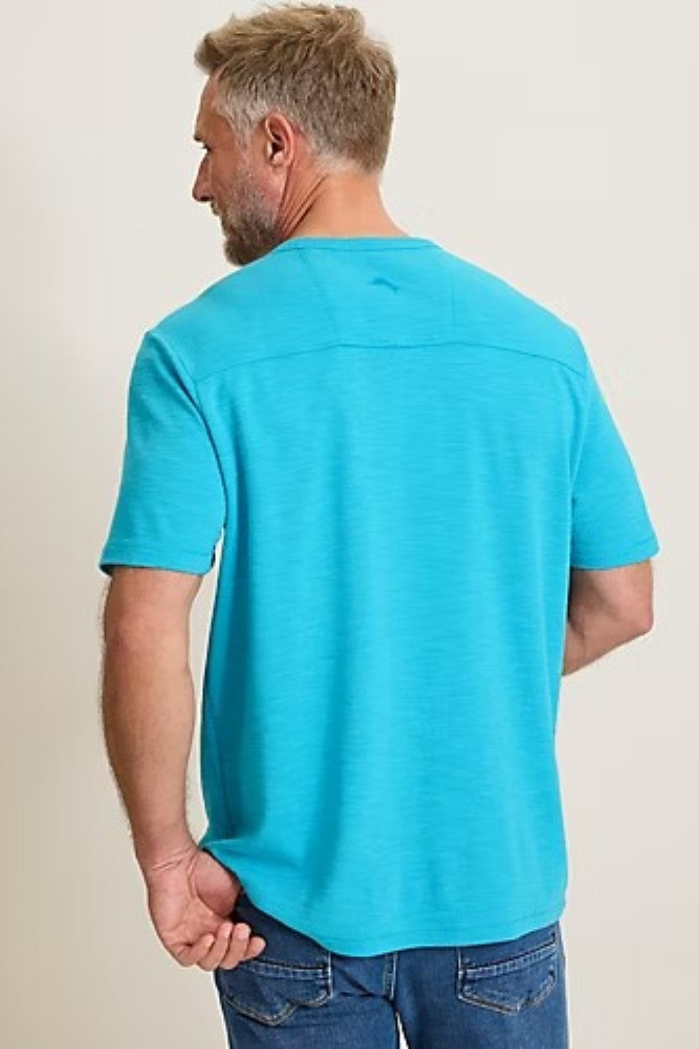 Man wearing a turquoise t-shirt against a plain background