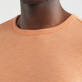 Close-up of a person wearing an orange sweater against a light background