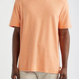 Person wearing an orange t-shirt and beige pants on a white background