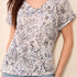 Woman wearing a patterned top and jeans on a plain background