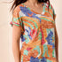 Woman wearing a colorful patterned top with a blurred background