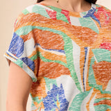 Person wearing a colorful patterned top with a neutral background