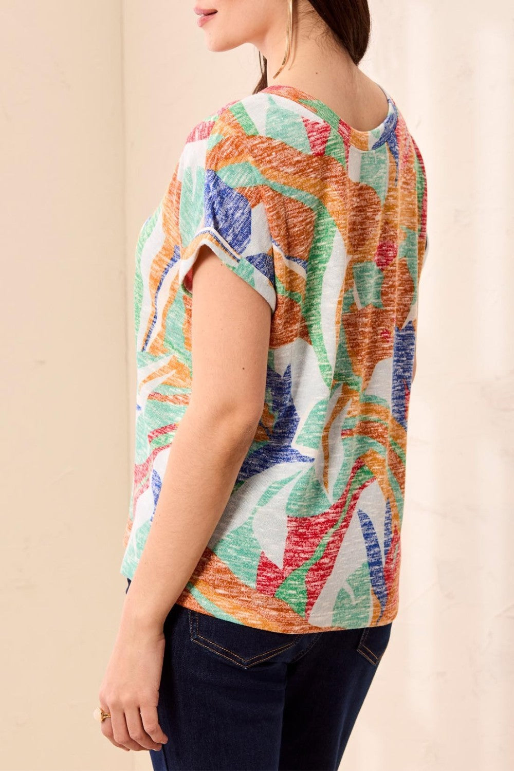 Person wearing a colorful patterned shirt against a beige background