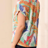 Person wearing a colorful patterned shirt against a beige background