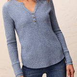Woman wearing a blue long-sleeve henley shirt with a neutral background