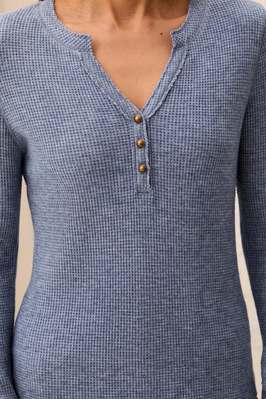 Blue textured long-sleeve shirt with button details on a neutral background