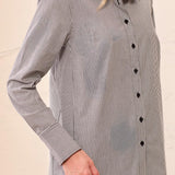Woman wearing a black and white striped shirt against a beige background