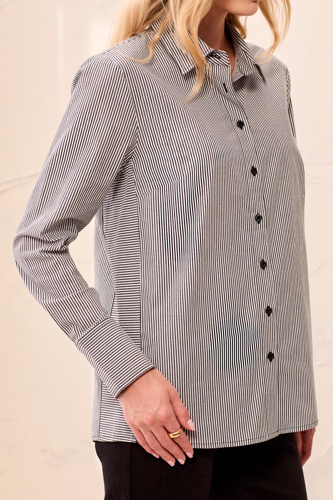 Woman wearing a black and white striped shirt against a beige background
