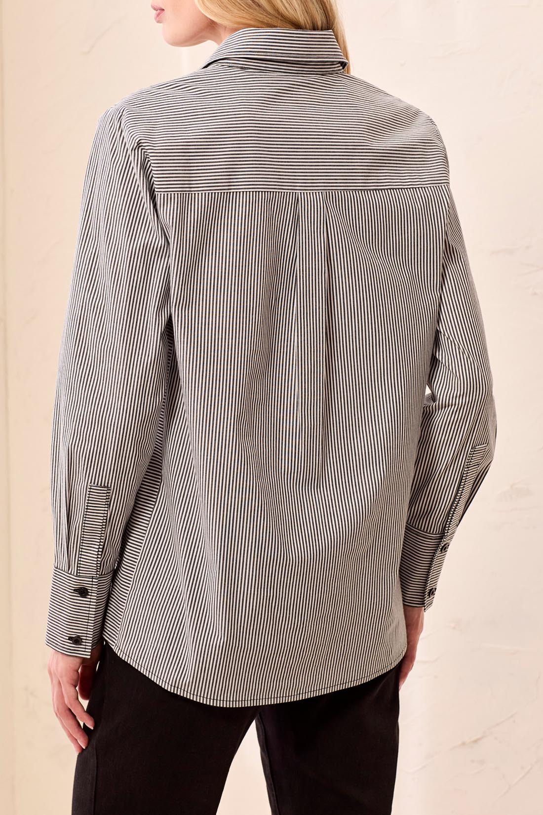 Person wearing a black and white striped shirt against a beige background