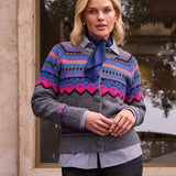 Woman wearing a patterned sweater over a striped shirt standing outdoors.
