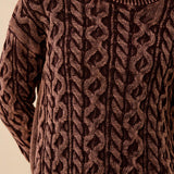 Close-up of a brown cable knit sweater on a neutral background
