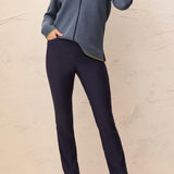 Woman wearing a blue top and navy pants against a light background