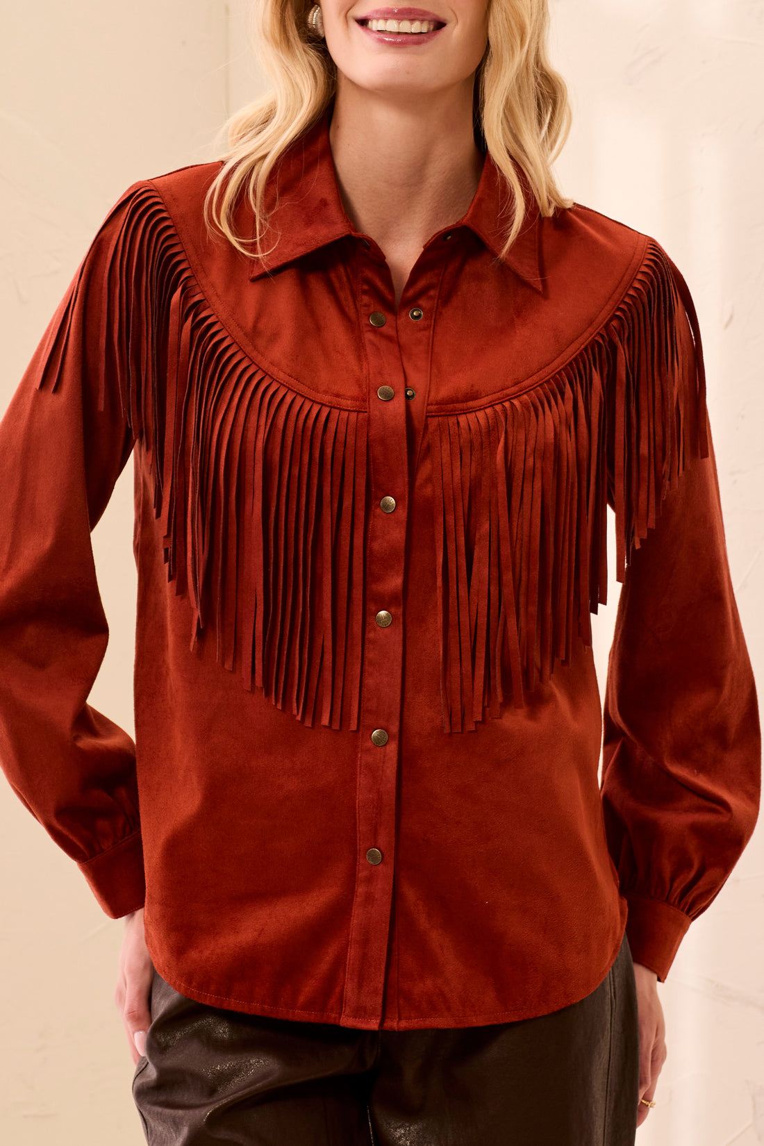 Woman wearing an orange fringed shirt with a blurred background
