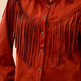 A close-up of a rust-orange suede western-style shirt jacket with a pointed collar, button front, and long fringe across the chest and shoulders.