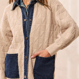Person wearing a beige cable knit sweater with blue denim pockets, placket and collar against a light background