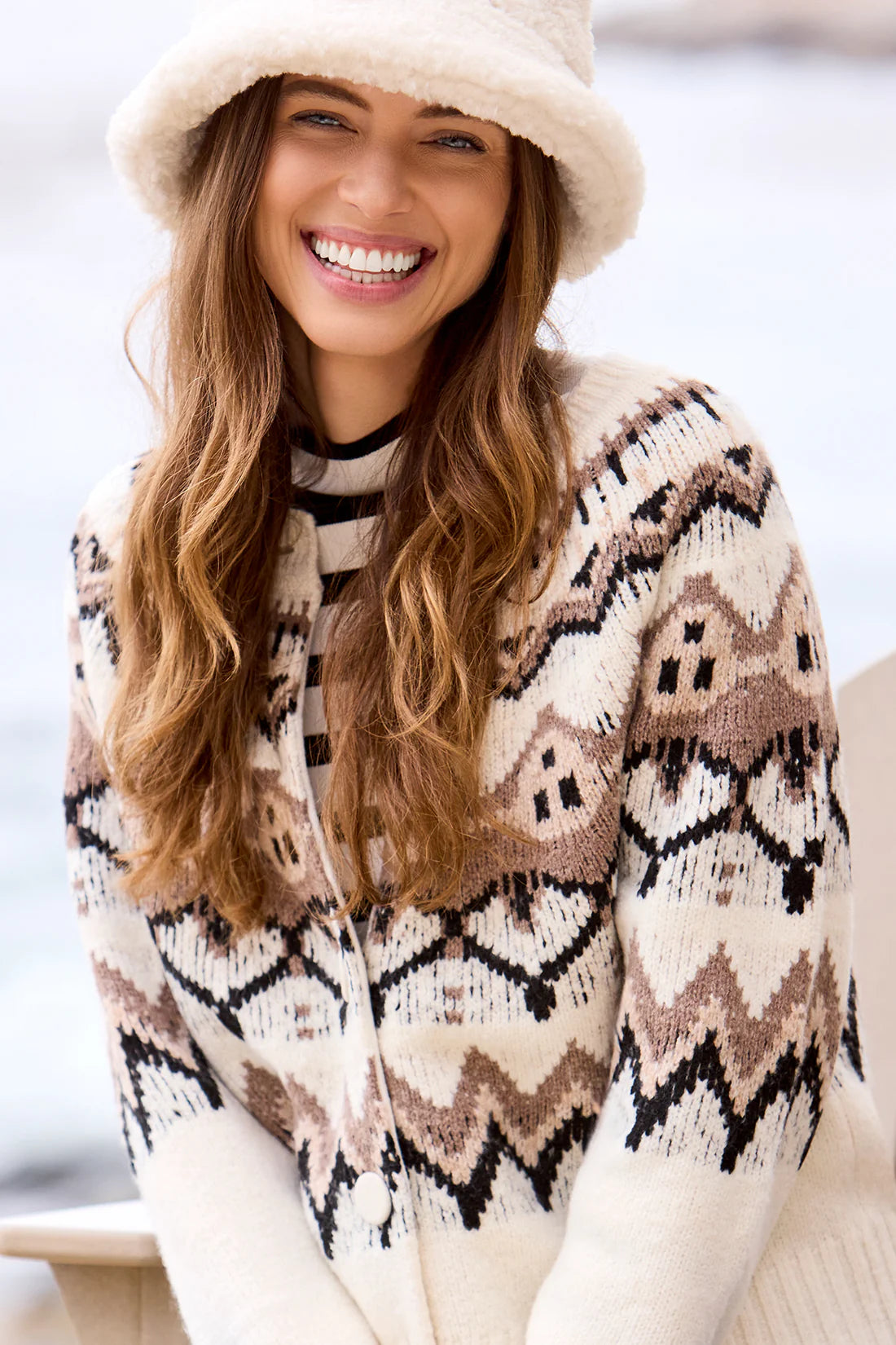 Woman wearing a patterned cardigan and hat with a blurred background