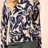 Woman wearing a blue and beige patterned sweater with striped pants on a light background