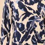Woman wearing a blue and beige patterned sweater with striped pants on a light background