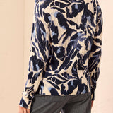 Woman wearing a blue and beige patterned sweater with striped pants on a light background