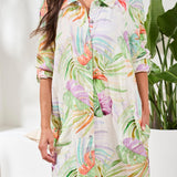 Woman wearing a colorful floral dress with a blurred indoor background