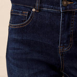 Close-up of dark blue jeans with a beige background