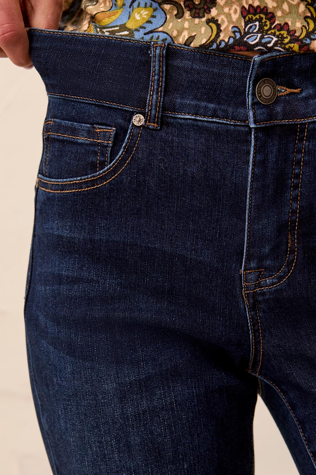 Close-up of dark blue jeans with a beige background