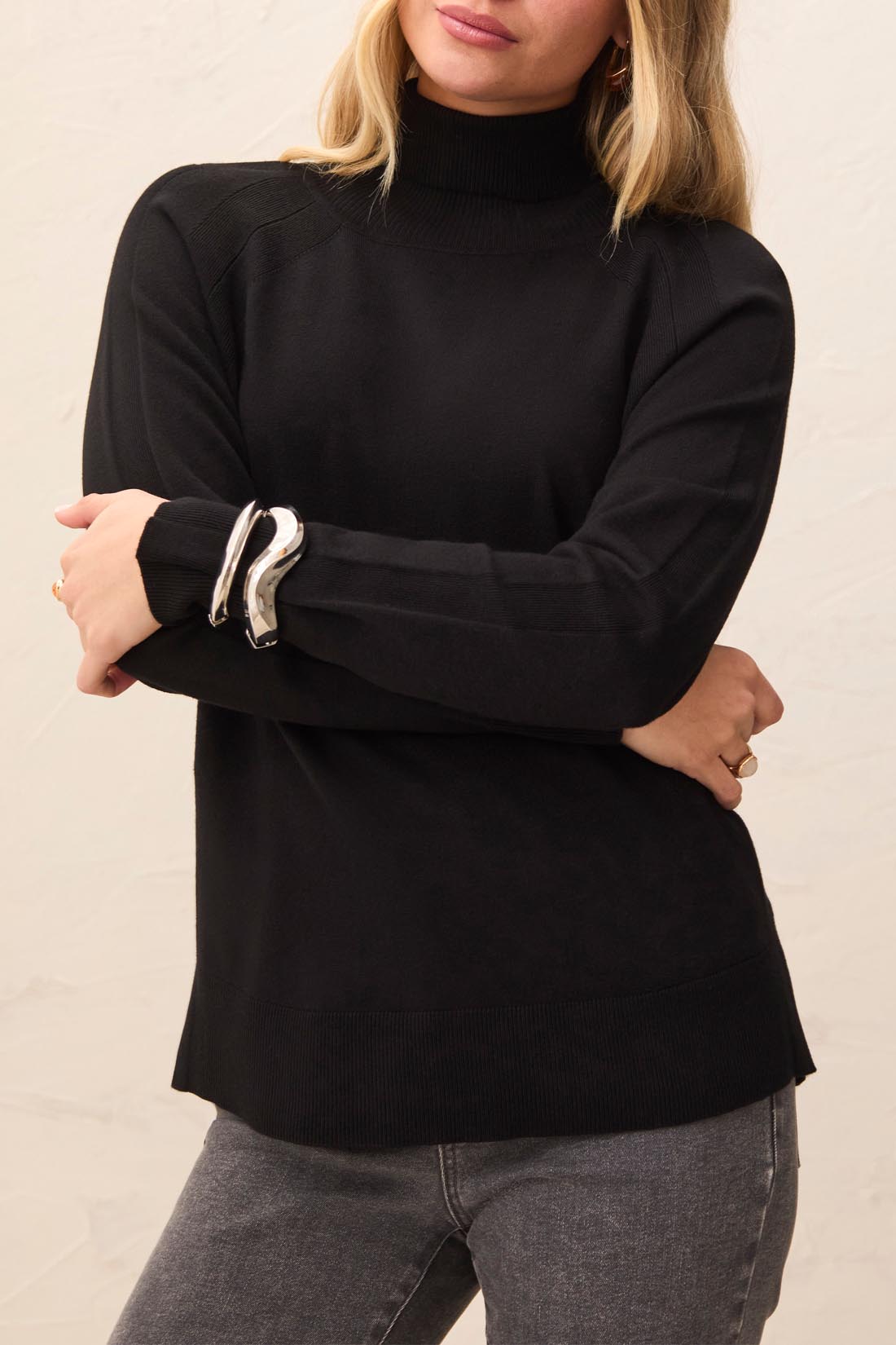 Person wearing a black turtleneck sweater against a neutral background