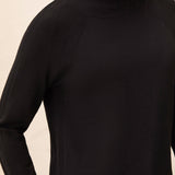 Black turtleneck sweater worn by a person on a beige background
