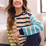Woman wearing a striped sweater sitting on a couch in a bright room.