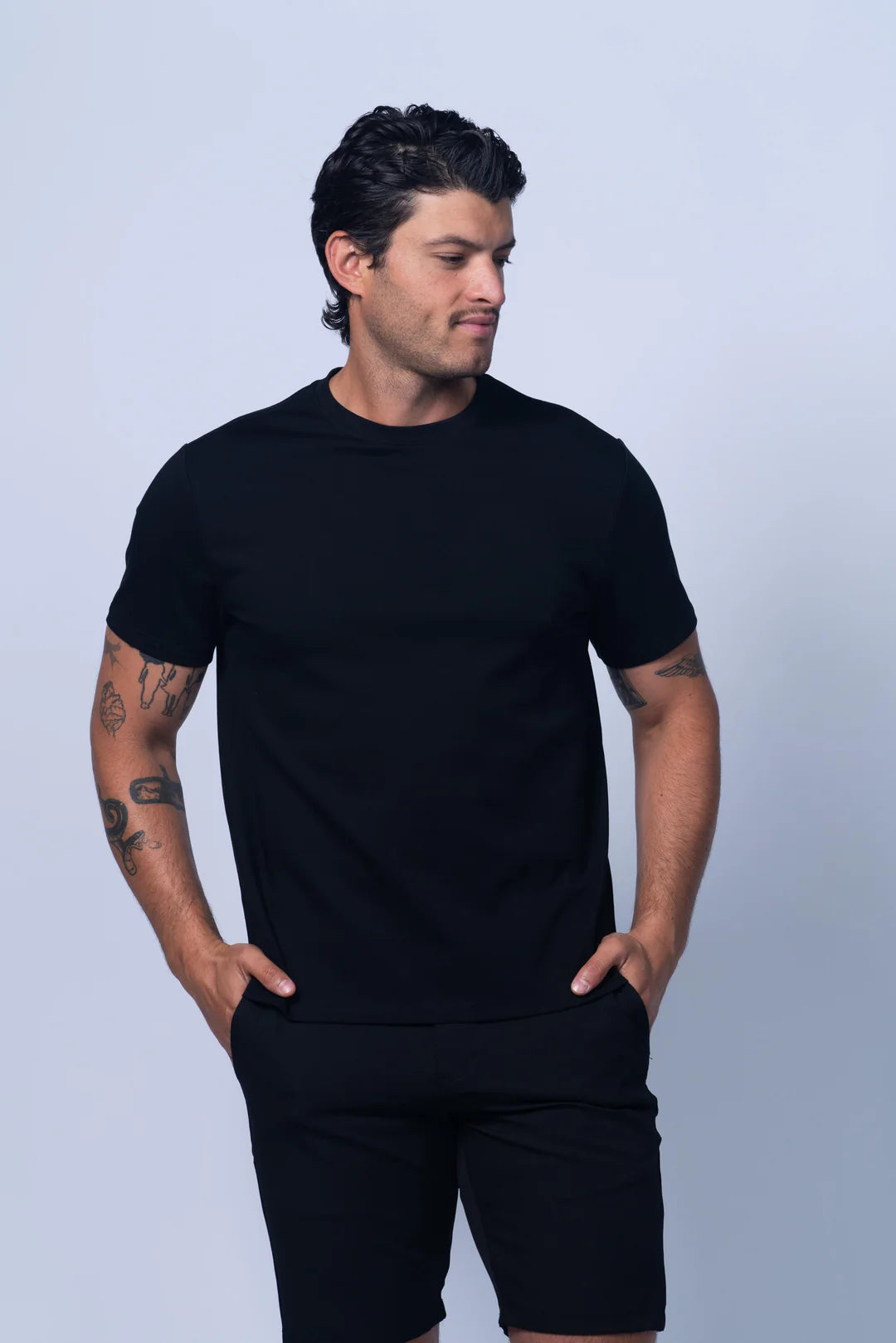 Man wearing a black t-shirt and shorts against a light gray background