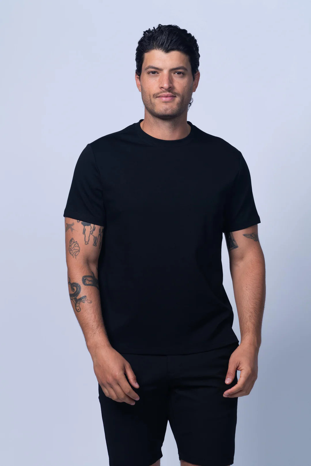 Man wearing a black t-shirt and shorts on a light gray background