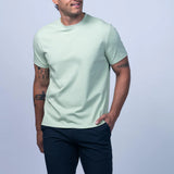 Man wearing a light green t-shirt and navy shorts on a light gray background