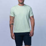 Man wearing a light green t-shirt and navy shorts on a plain background