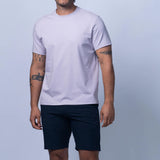 Man wearing a light gray t-shirt and navy shorts on a light gray background
