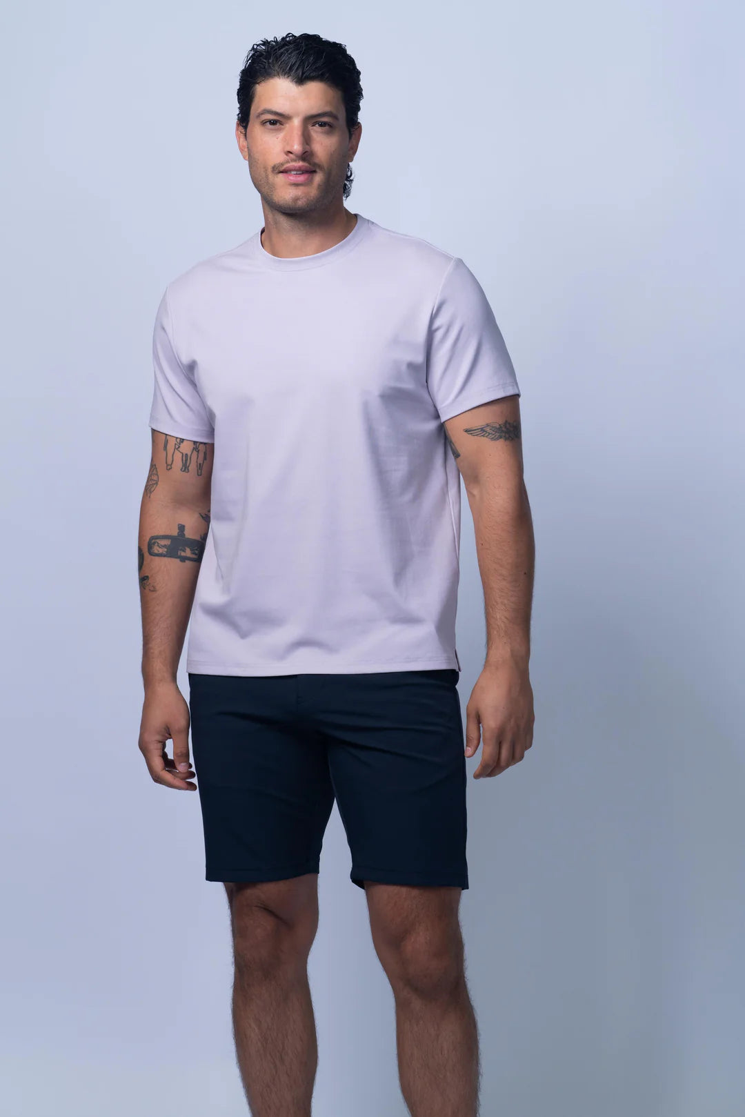 Man wearing a light gray t-shirt and navy shorts on a light gray background