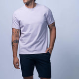 Man wearing a plain white t-shirt and black shorts on a light gray background