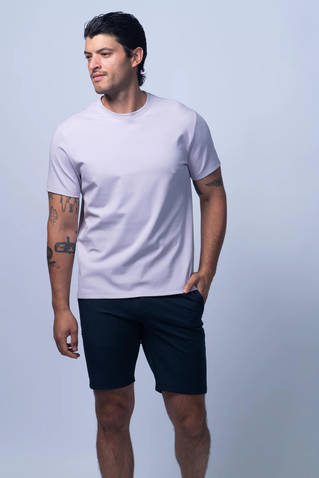 Man wearing a plain white t-shirt and black shorts on a light gray background