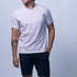 Man wearing a plain white t-shirt and black shorts on a light gray background