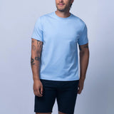 Man wearing a light blue t-shirt and dark shorts on a light gray background