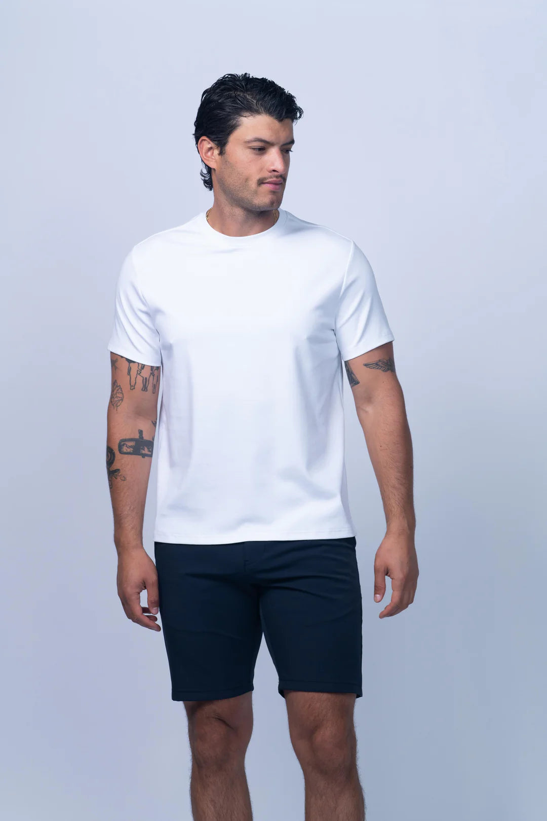 Man wearing a white t-shirt and navy shorts on a light gray background