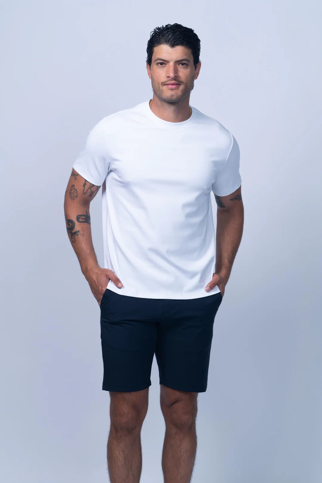 Man wearing a white t-shirt and navy shorts on a light gray background