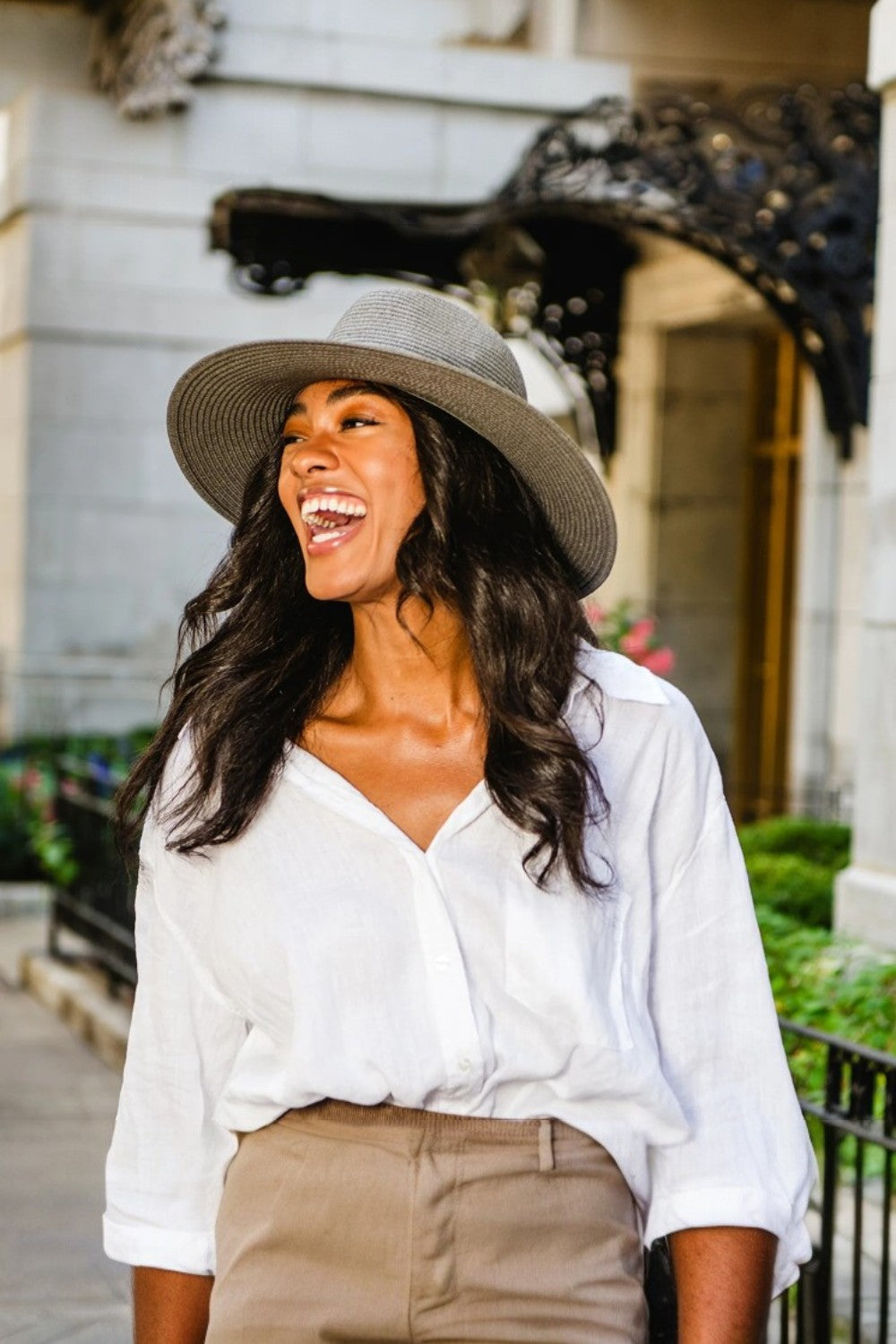 Woman wearing a wide-brimmed hat and white shirt in an urban setting