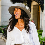 Woman wearing a wide-brimmed hat and white shirt in an urban setting
