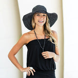 Woman wearing a black strapless top and wide-brimmed hat against a white background