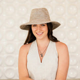 Woman wearing a light hat against a textured white background