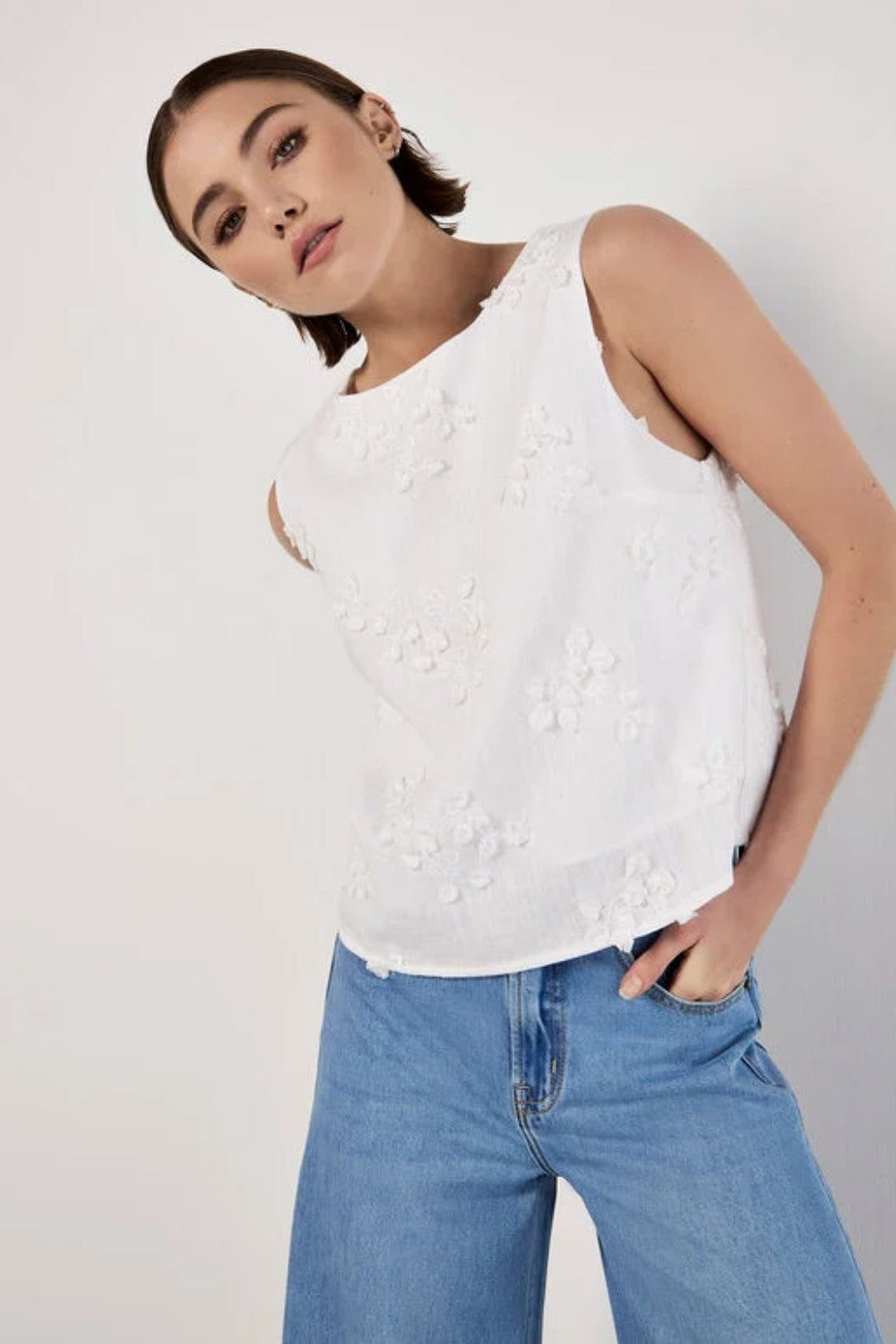 This summer-ready shell top features feminine floral and leaf applique. Cut from a woven fabric to a textured finish, it's lined for comfort and boasts a crew neck and button-down back. Style it with a pencil skirt for all your warm-weather plans.