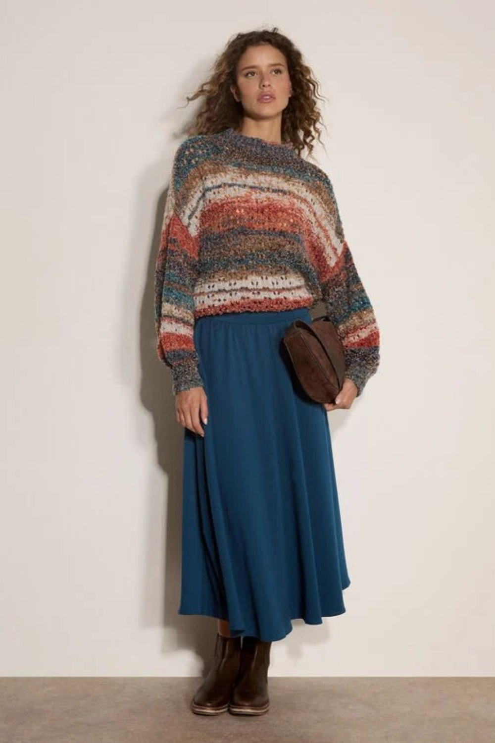 Broderick's Clothing Co. apricot mixed yarn boho jumper with open-knit stripes and mock neck worn with a blue skirt.