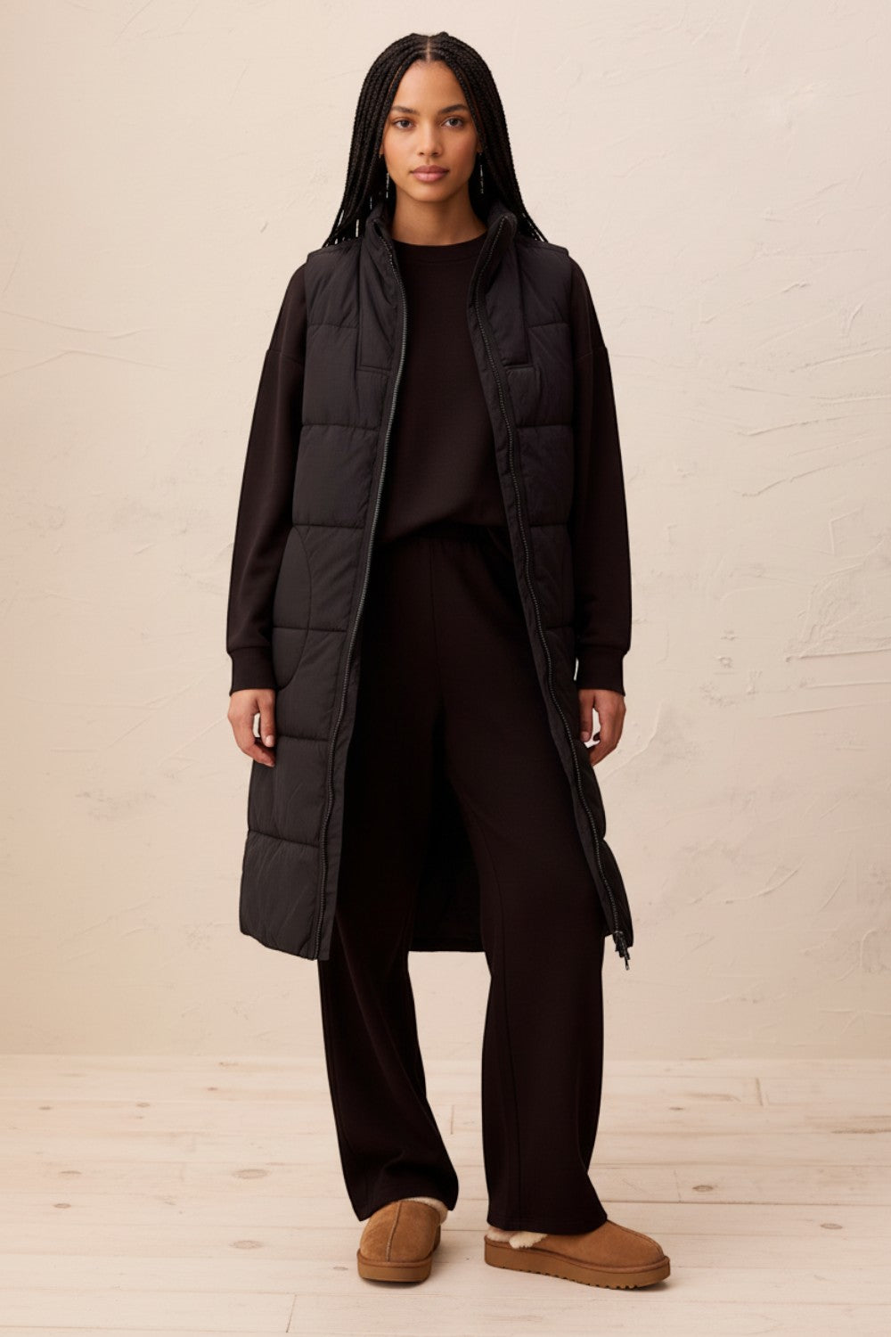 Broderick's Clothing Co. long black quilted vest with a zip-front closure worn by a model in a studio setting.