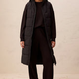 Broderick's Clothing Co. long black quilted vest with a zip-front closure worn by a model in a studio setting.